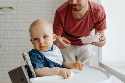 Father feeding baby in high chair
