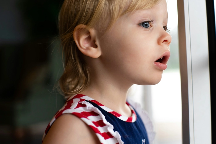 Curious young girl looking out the window