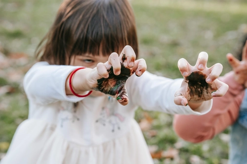 Girl showing hands covered in paint outdoors