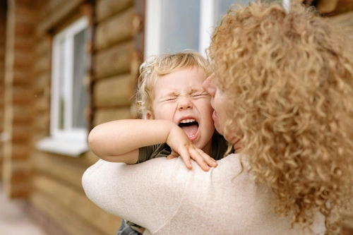 Woman holding crying toddler outdoors