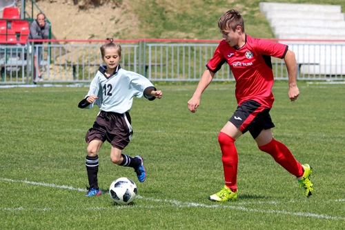 Two children playing soccer on a grassy field