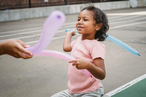 Child playing with balloon swords outdoors