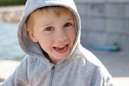 Happy young boy in gray hoodie grinning widely