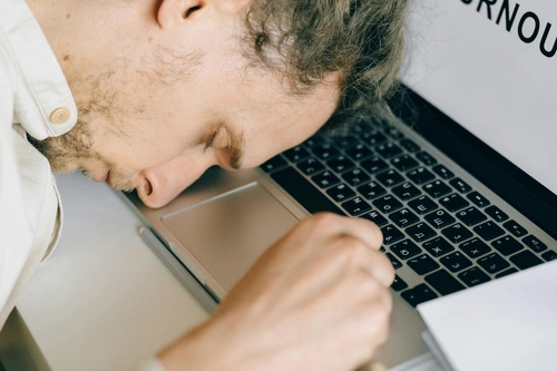 Overworked man falling asleep with his face laid on laptop keyboard