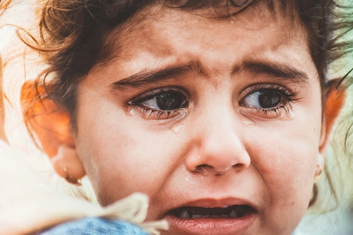 Upset girl with tears streaming down her cheeks, looking heartbroken.